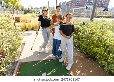 Group of smiling friends enjoying together playing mini golf in the city. - Powered by Shutterstock