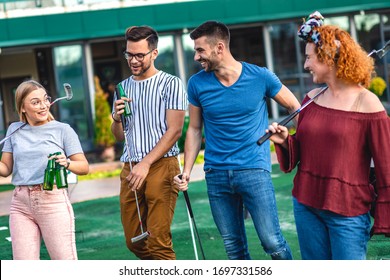 Group Of Smiling Friends Going To Play Mini Golf In The City.