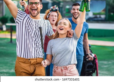 Group Of Smiling Friends Going To Play Mini Golf In The City.