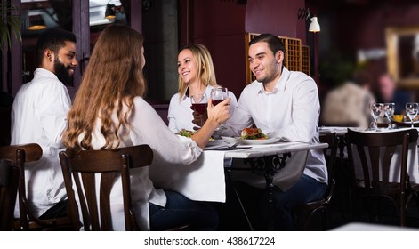 Group Of Smiling Friends Having Dinner In Restaurant And Laughing