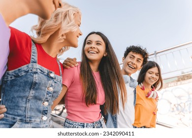 Group of smiling friends, multiracial teenagers wearing colorful casual clothes embracing, walking on the street. Happy stylish boys and girls outdoors. Friendship, positive lifestyle, diversity - Powered by Shutterstock