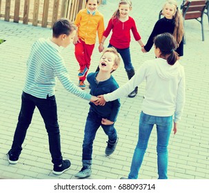 Group Of Smiling Glad Children Playing Red Rover Outdoors