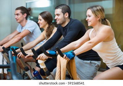 Group smiling happy working out of cycling in modern fitness club