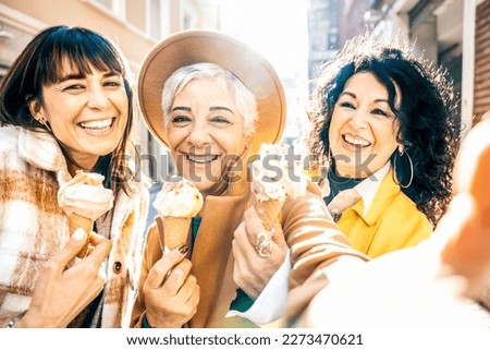 Group of smiling mature women eating ice cream cone outside in a sunny day - Three older friends girls take a happy selfie while walking at city - Concept about elderly people, food and joyful weekend
