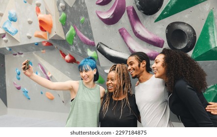 Group of smiling multi-cultural friends posing for selfie by climbing wall at indoor activity centre - Powered by Shutterstock