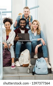 Group Of Smiling Multicultural Students With Laptop Showing Thumbs Up In University