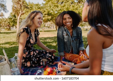 Group Of Smiling Multiracial Female Best Friends Sitting Together On Blanket With Fruits Enjoying At Picnic In The Park - Group Of Healthy Friends Having A Picnic