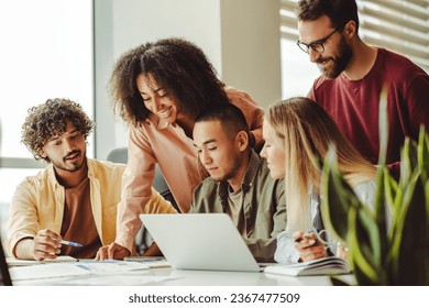 Group of smiling multiracial university students using laptop exam preparation studying together. Education concept. Young team, colleagues meeting, working, planning startup project in modern office  - Powered by Shutterstock