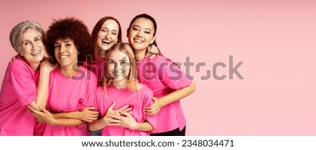 Group of smiling multiracial women wearing t shirts with pink ribbon looking at camera isolated on pink  background, copy space. Health care, support, prevention. Breast cancer awareness month concept