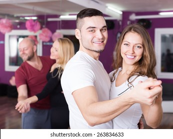 Group of smiling positive young adults dancing at dance class. Focus on guy