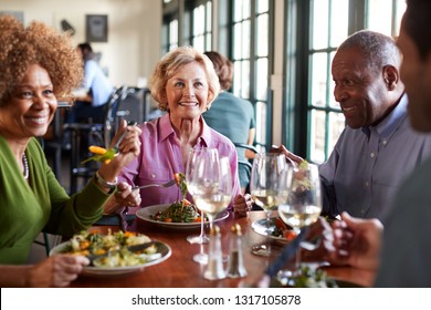 Group Of Smiling Senior Friends Meeting For Meal In Restaurant