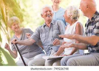 Group Of Smiling Senior Friends Spending Time Together Sitting In The Park