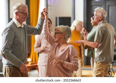 Group of smiling senior people dancing while enjoying activities in retirement home, copy space - Powered by Shutterstock