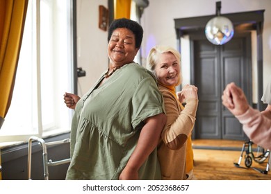 Group of smiling senior women dancing while enjoying activities in retirement home, copy space - Powered by Shutterstock