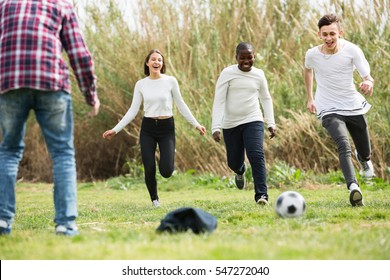 Group of smiling  teenage friends playing football outdoors in autumn day - Shutterstock ID 547272040