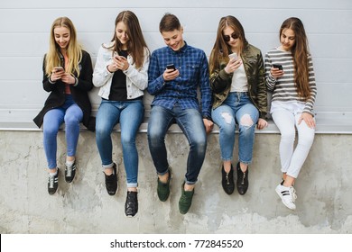 Group Of Smiling Teenagers With Smartphone Skateboard.