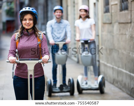 Group of smiling three friends posing on segways in vacation on city street