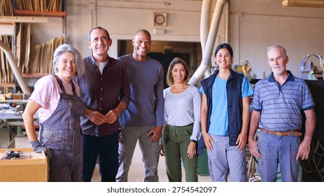 Group of smiling workers from different generations and ethnicities standing together in a woodworking factory