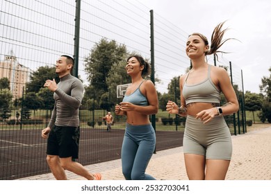 Group of smiling, young, active, multinational people, sportswomen and man wearing stylish sportwear running together, having morning run on the street, outdoors. Sport, movement, motivation concept