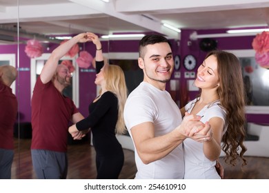 Group of smiling young adults dancing salsa in club