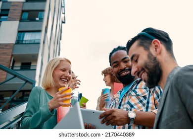 Group Of Smiling Young Diverse Business People With Laptop Outdoor In Coffee Break. Multiracial Colleagues In Casual Talk. Copy Space