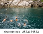 A group of snorkelers explores the clear, turquoise waters near rocky cliffs, eager to discover the underwater world.