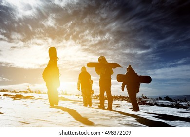 Group Snowboarders Goes To Sunset. Snowboarding Concept