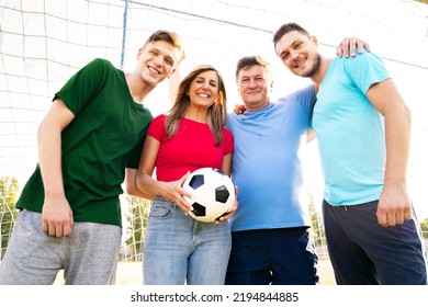 Group Of Soccer Fans Hugging In Front Of Goal And Holding Soccer Ball 