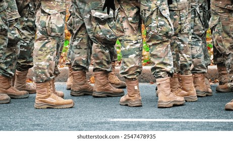 Group of Soldiers Wearing Camouflage Unifroms and Tactical Boots Standing on Asphalt Road - Powered by Shutterstock