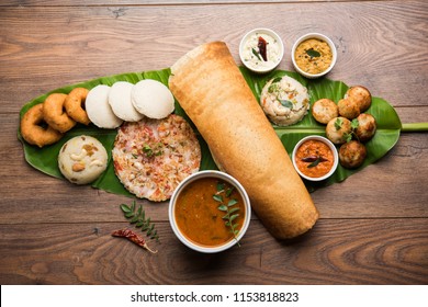 Group of South Indian food like Masala Dosa, Uttapam, Idli/idly, Wada/vada, sambar, appam, semolina halwa, upma served over banana leaf with colourful chutneys, selective focus