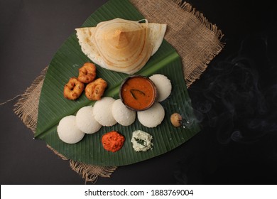 Group Of South Indian Food Like Masala Dosa, Idli, Wada Or Vada, Sambar, Served Over Banana Leaf With Colourful Coconut Chutneys