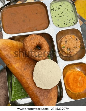 Group of South Indian food like Masala Dosa, Uttapam, Idli, idly, Wada, vada, sambar, appam, semolina halwa, upma served over banana leaf with colourful chutneys, selective focus