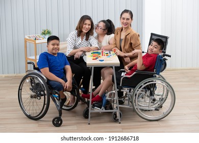 Group of special students in classroom, a down syndrome girl, two handicapped boys and cute Asian teacher playing toy and game together.