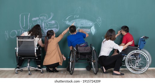 Group of special students in classroom, a down syndrome girl, two handicapped boys and  two female teachers drawing and painting on black board together. - Powered by Shutterstock