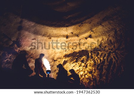 Group of speleologists resting and cooking on gas fire during a cave exploration. Discovering unexplored underground places by spelunkers