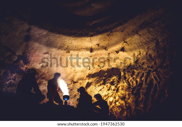 Group of speleologists resting and cooking on\
gas fire during a cave exploration. Discovering unexplored\
underground places by\
spelunkers