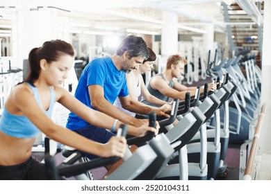 Group, spin class or mature man on cycling machine in training or exercise for wellness or fitness. Active club, healthy or people on bicycle for cardio, power for workout, body or sports on bike - Powered by Shutterstock