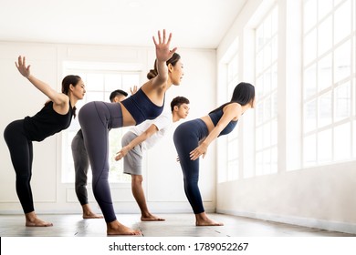 Group of sporty attractive asian people wearing sportswear bra pants practicing yoga lesson on Uttanasana pose Standing Forward Bend with instructor coach. Work out fitness healthy lifestyle concept.