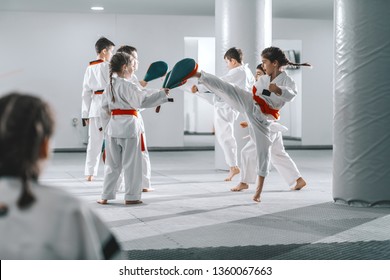 Group Of Sporty Caucasian Children In Doboks Having Taekwondo Class In White Gym.