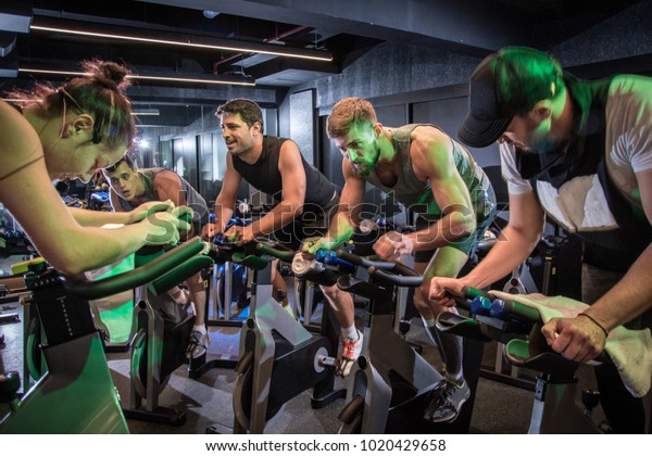 Group of sporty people\
cycling at gym.