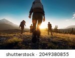 Group of sporty people walks in mountains at sunset with backpacks. Altai mountains, Siberia, Russia.