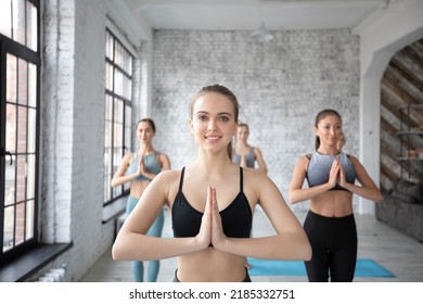 Group Of Sporty Women Doing Yoga Exercises In Gym Prayer Position Beautiful Slim Girls Wearing Sportswear Posing At Grey Fitness Center Wall Background.