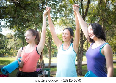 Group Sporty Women Of Mother And Her Daughter Standing With Mat In Yoga Sport Uniform Rejoice Raising Their Hands Up After Exercise In Outdoor Class. Team, Friendship And Helthy Lifestyle Concept.