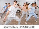 Group of sporty young adult multinational sports people making straight line with hands exercising dancing in gym