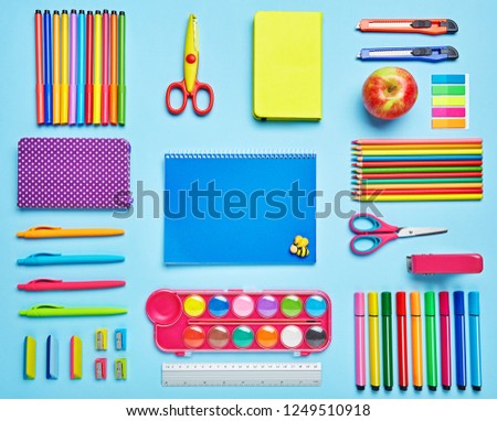 Group stationery set forth in composition on a blue background. Top view, flat lay. copyspace