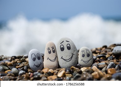 Group of stones with drawn faces in the sand. Father, mother, daughter and son. Concept of happy family