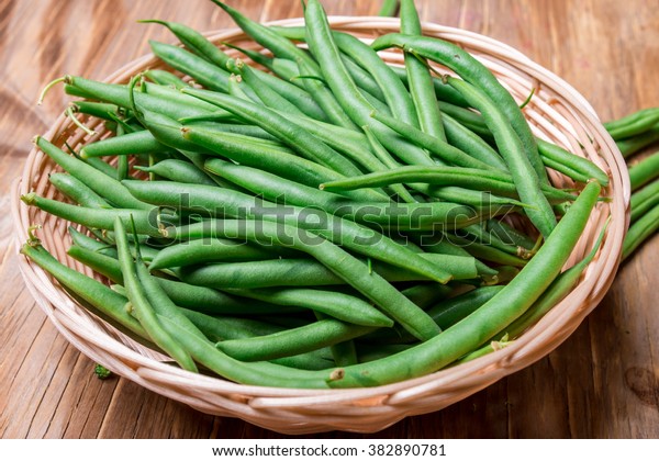 group of string beans also call green bean in a\
bamboo basket on a wooden\
table