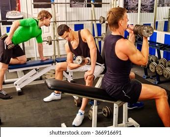Group of strong men hard working on simulator his body at gym. 