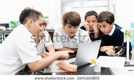 Group of student boys focus on laptop, collaborate in classroom. Boys in school uniforms teamwork, learn together, discuss ideas in classroom. Student focus on group project, work together on laptop