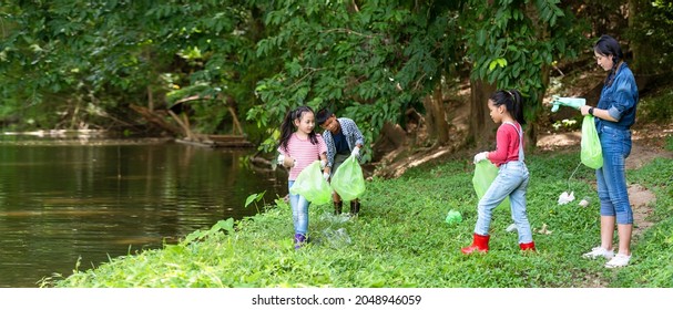 Group student Charity and recycle plastic for environment.  People asia girl  and boy collecting garbage and plastic on the nature river to dumped into the trash for keep nature.  Save environment